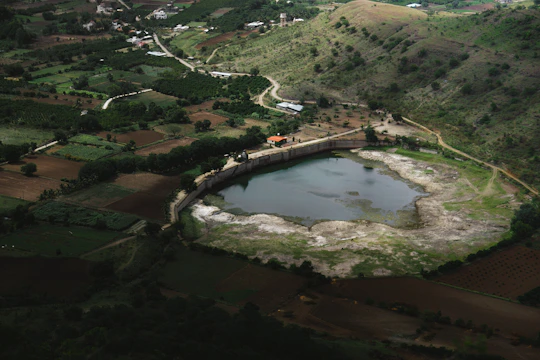 A freshly dug pond nestled in a rural landscape with earthmoving equipment nearby.