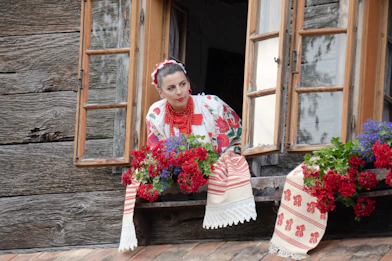 a woman sitting on a window sill with flowers