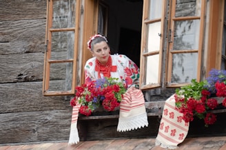 a woman sitting on a window sill with flowers