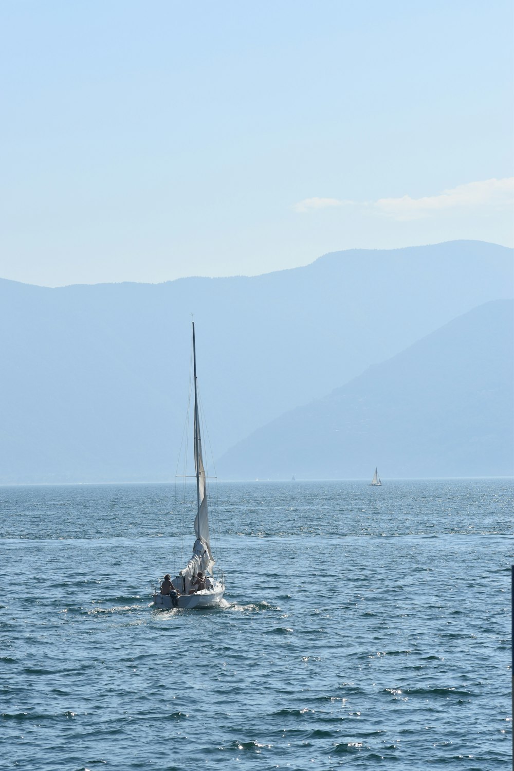 a sailboat in the water with mountains in the background