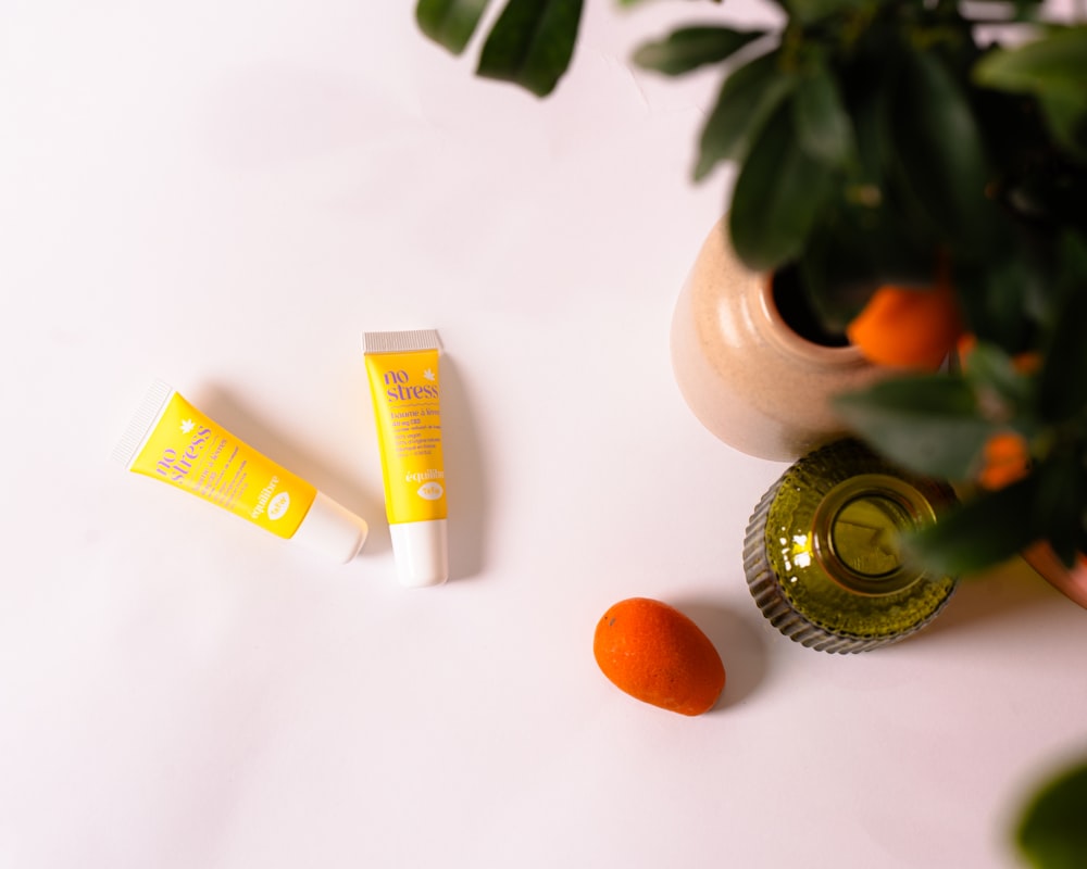 a bottle of lip butter next to some oranges