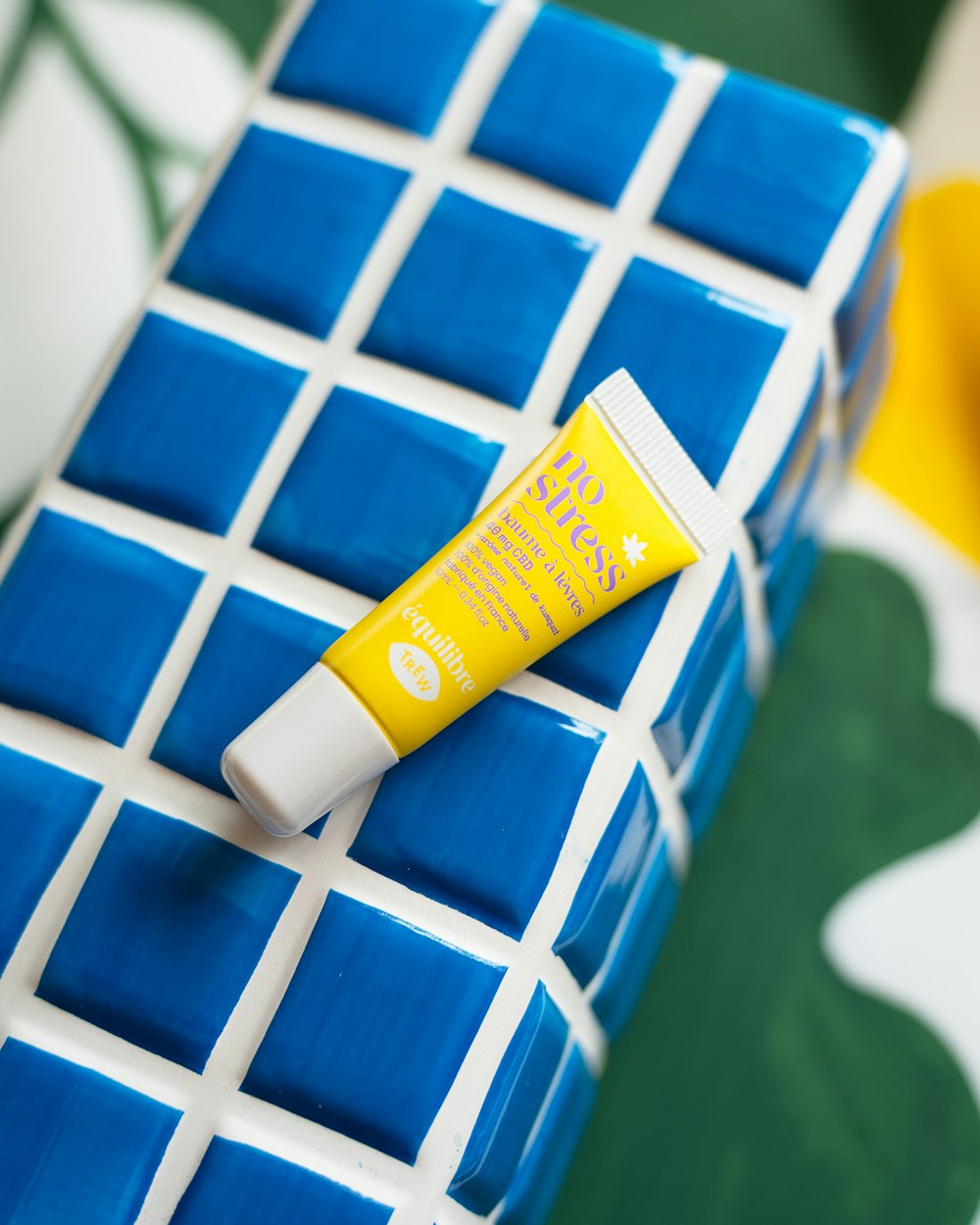 a tube of toothpaste sitting on top of a blue and white tiled surface