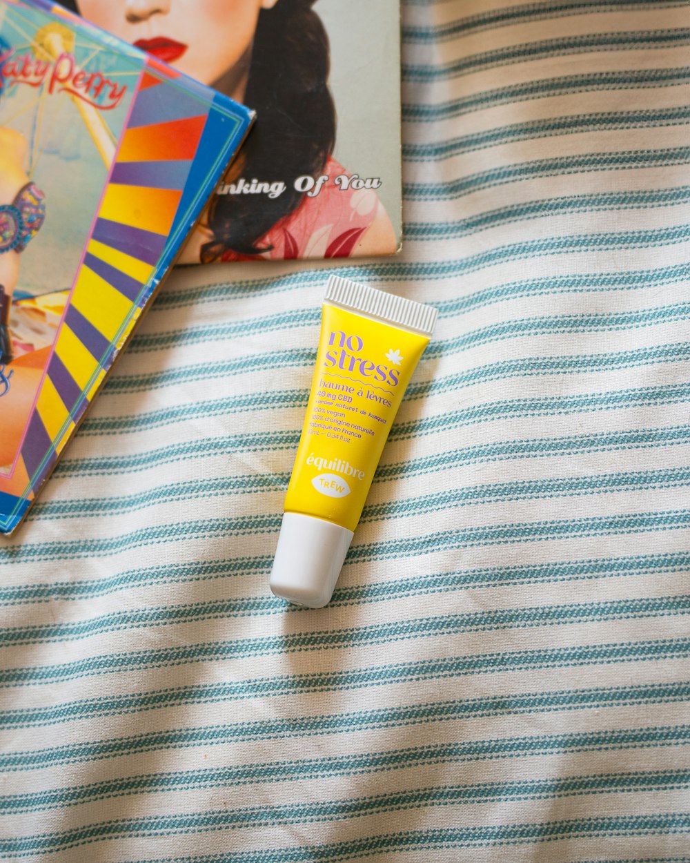 a tube of sunscreen next to a magazine on a bed