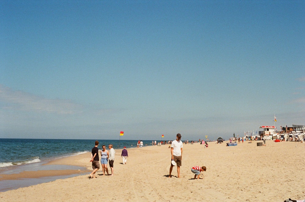 a group of people standing on top of a sandy beach