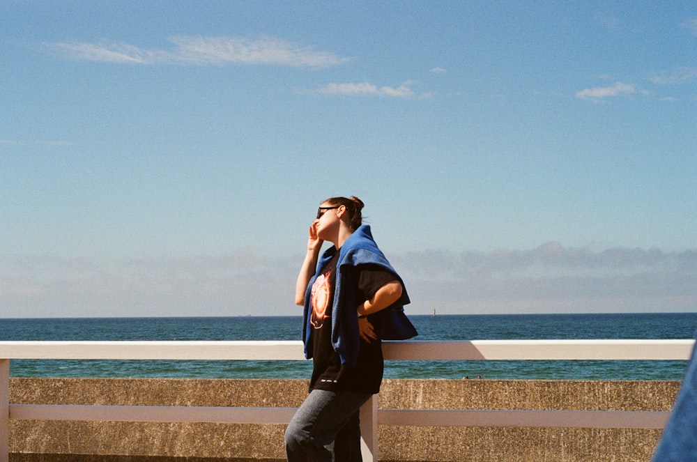 a man talking on a cell phone next to the ocean