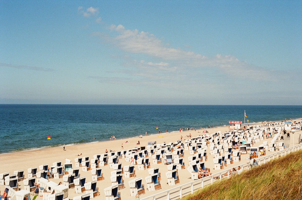 a beach filled with lots of lawn chairs next to the ocean