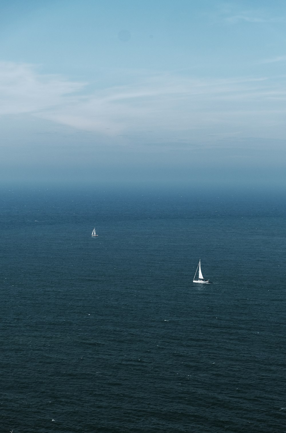 a couple of sail boats floating on top of a large body of water