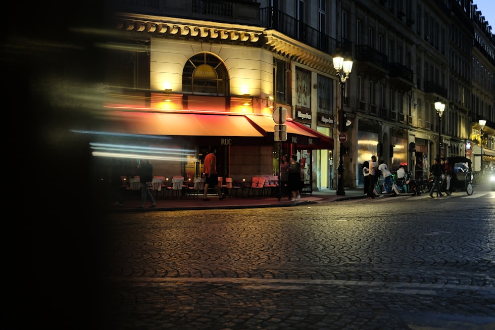 a city street at night with people walking on the sidewalk