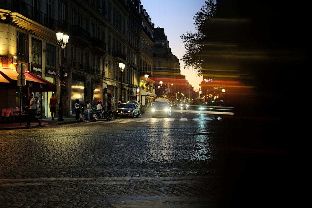 a city street at night with cars driving down it