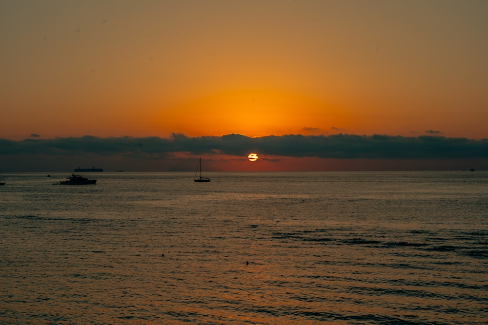 a sunset over the ocean with boats in the water