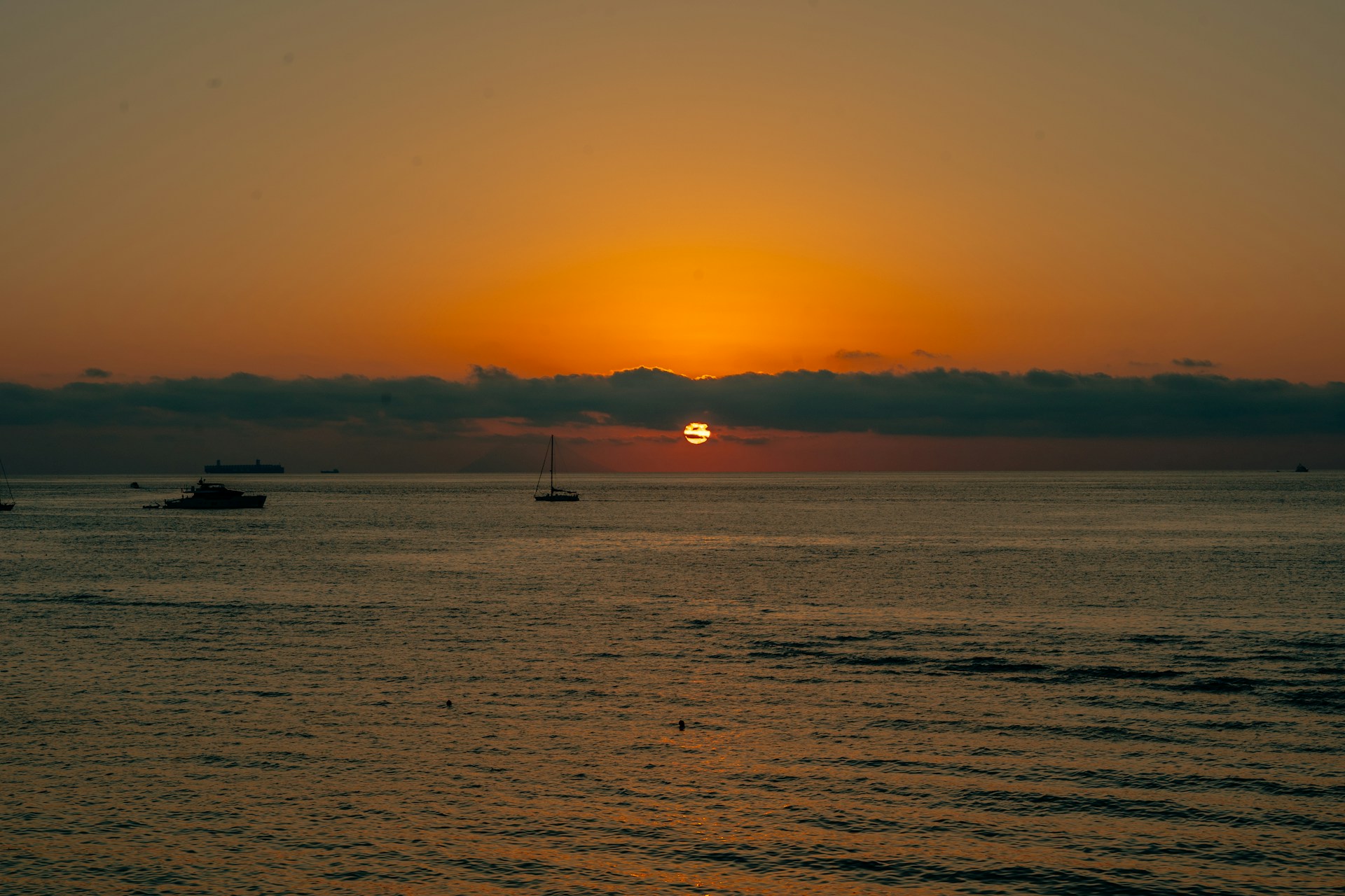 a sunset over the ocean with boats in the water