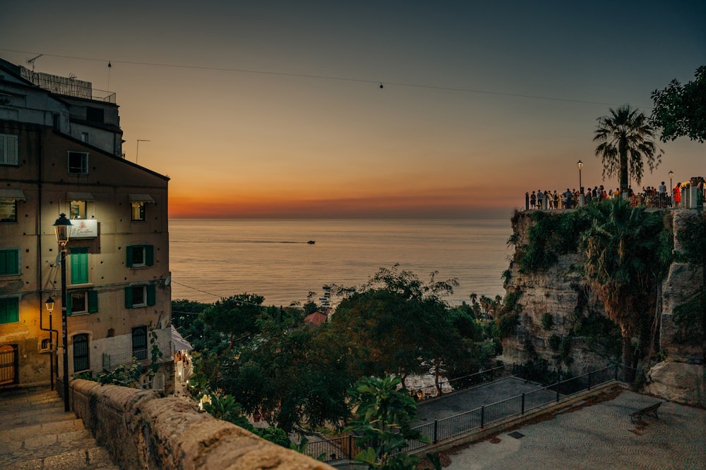 a group of people standing on top of a cliff next to the ocean