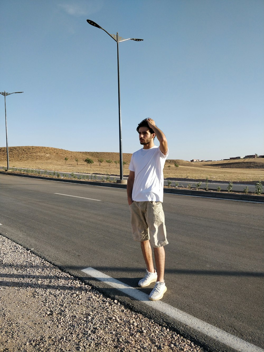 a man standing on the side of a road next to a street light