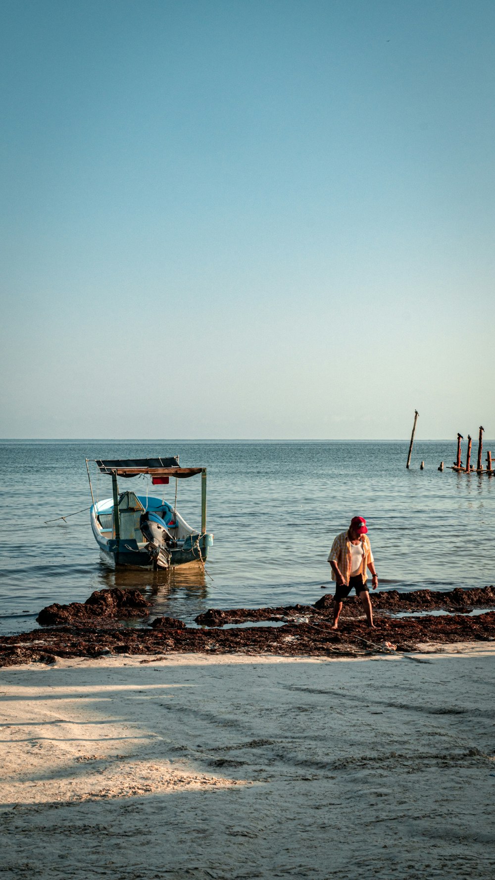 a man sitting on the shore of a beach next to a boat