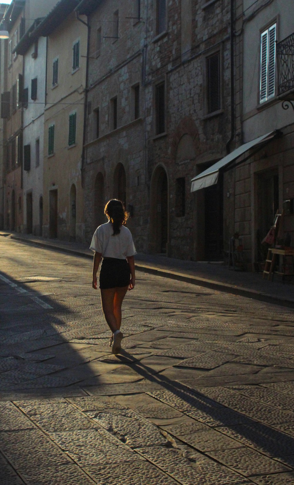 a woman walking down a street next to tall buildings