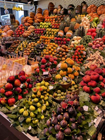 A lively market stall showcasing a variety of colorful fruits with the mascot playfully interacting.