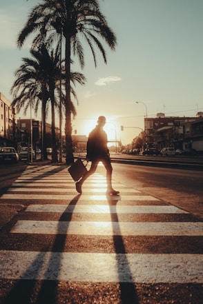 a man walking across a street holding a suitcase