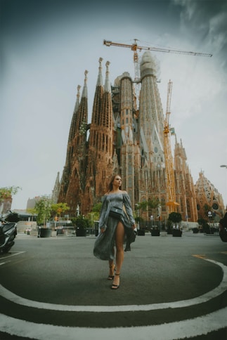 a woman walking down a street in front of a tall building