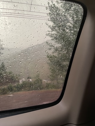 A serene morning scene with a journal, pen, and a window view of gentle rain outside.