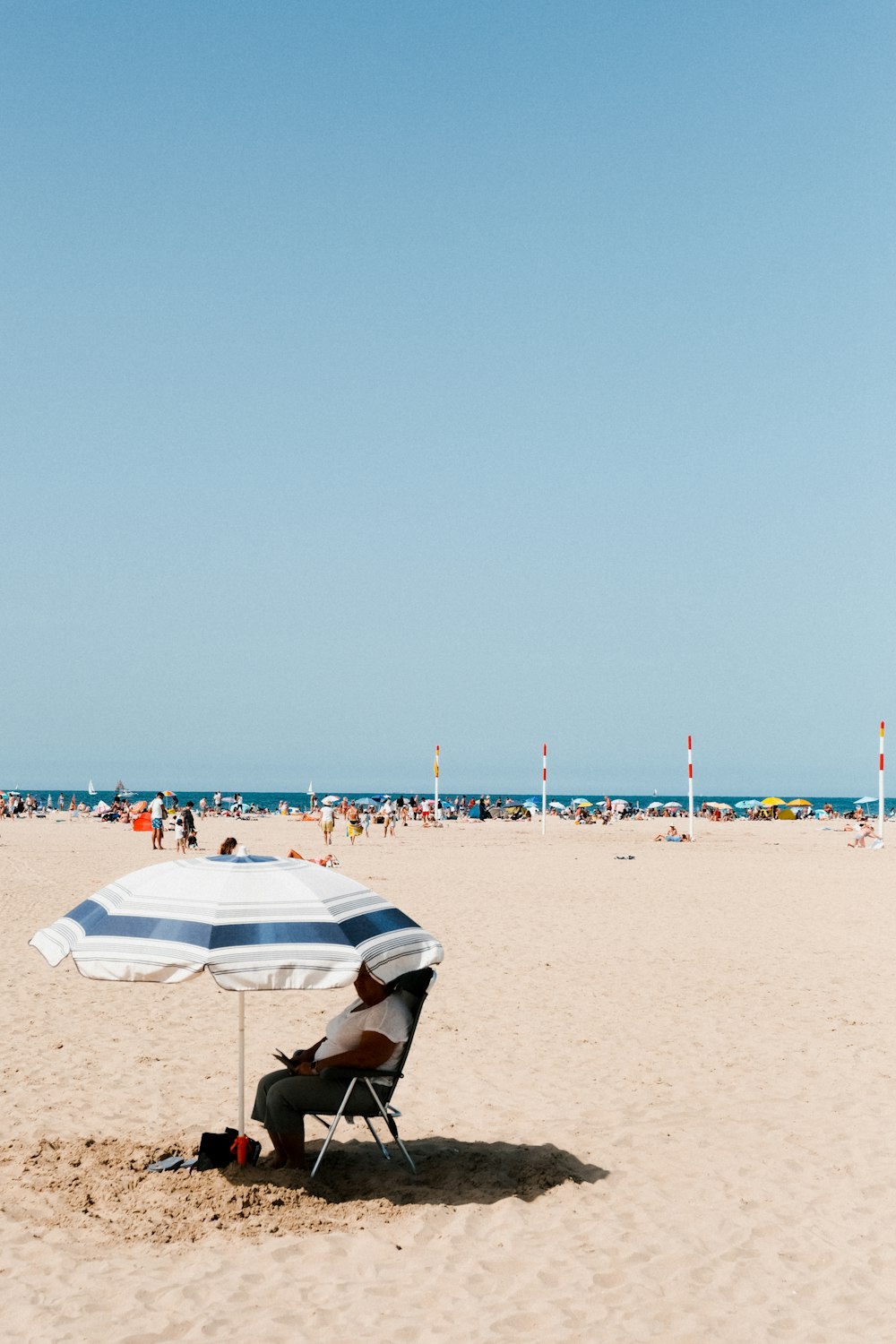 Ein Mann, der auf einem Stuhl unter einem Sonnenschirm am Strand sitzt