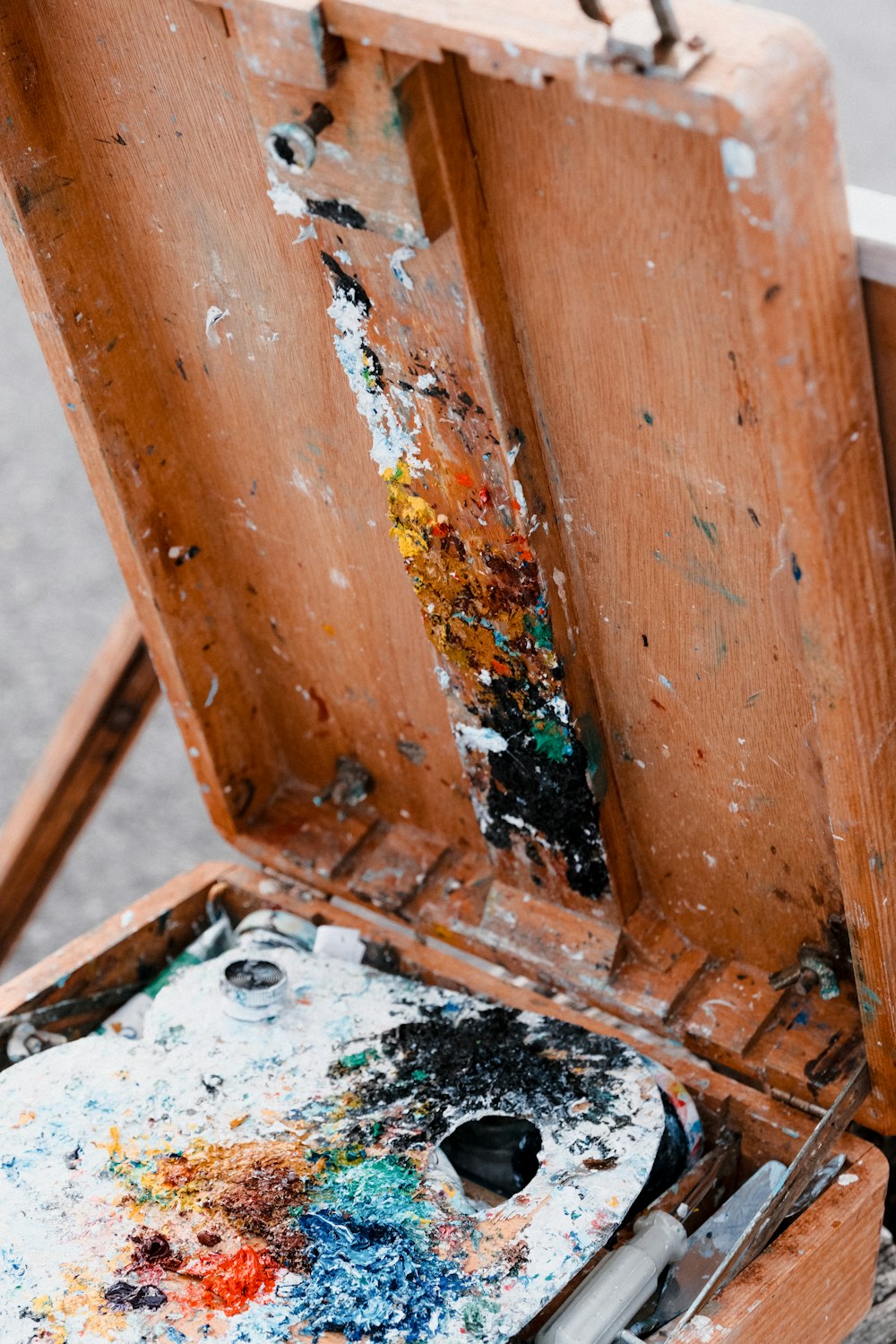 a wooden easel with paint and brushes in it