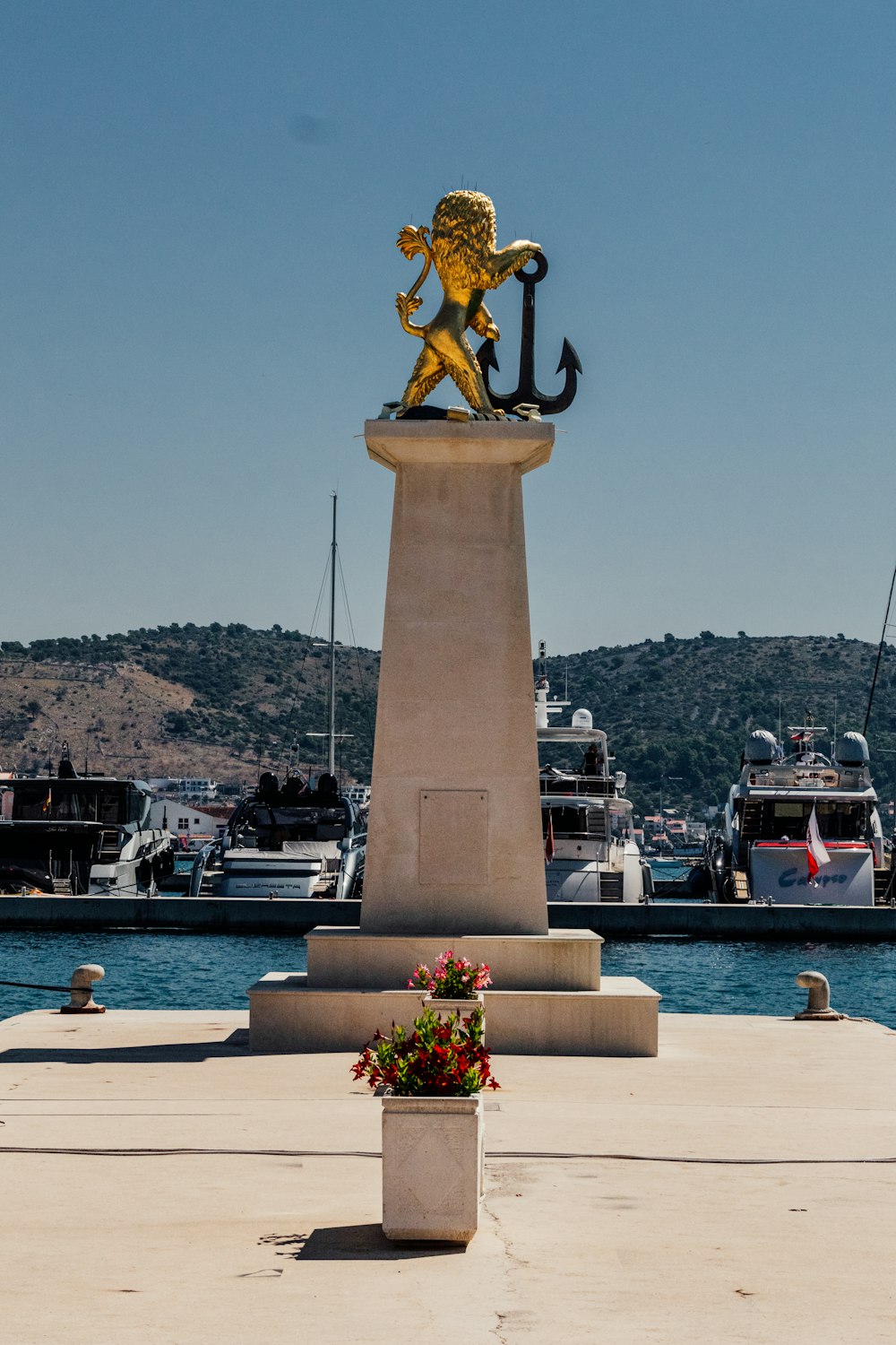 a statue of a lion on a pedestal in front of a harbor