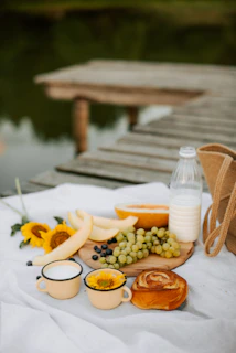 A rustic wooden picnic set arranged outdoors on a grassy patch with a checkered blanket and fresh fruits.