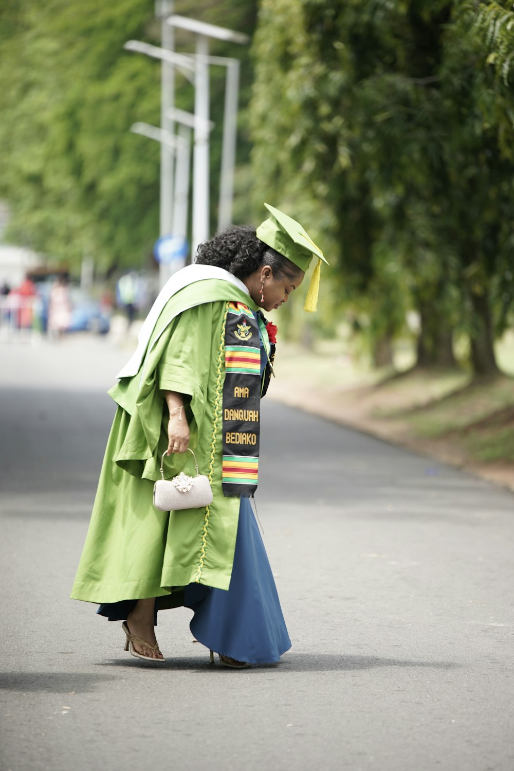 a woman in a graduation gown is walking down the street