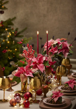 Elegant table setting with red and green floral arrangements and golden accents