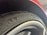 A close-up of a car tire with the 'Michelin' branding prominently displayed along with a small logo. The surrounding element of the car, possibly a wheel arch, is visible, and the tire appears new with clean tread patterns.
