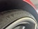 A close-up of a car tire with the 'Michelin' branding prominently displayed along with a small logo. The surrounding element of the car, possibly a wheel arch, is visible, and the tire appears new with clean tread patterns.
