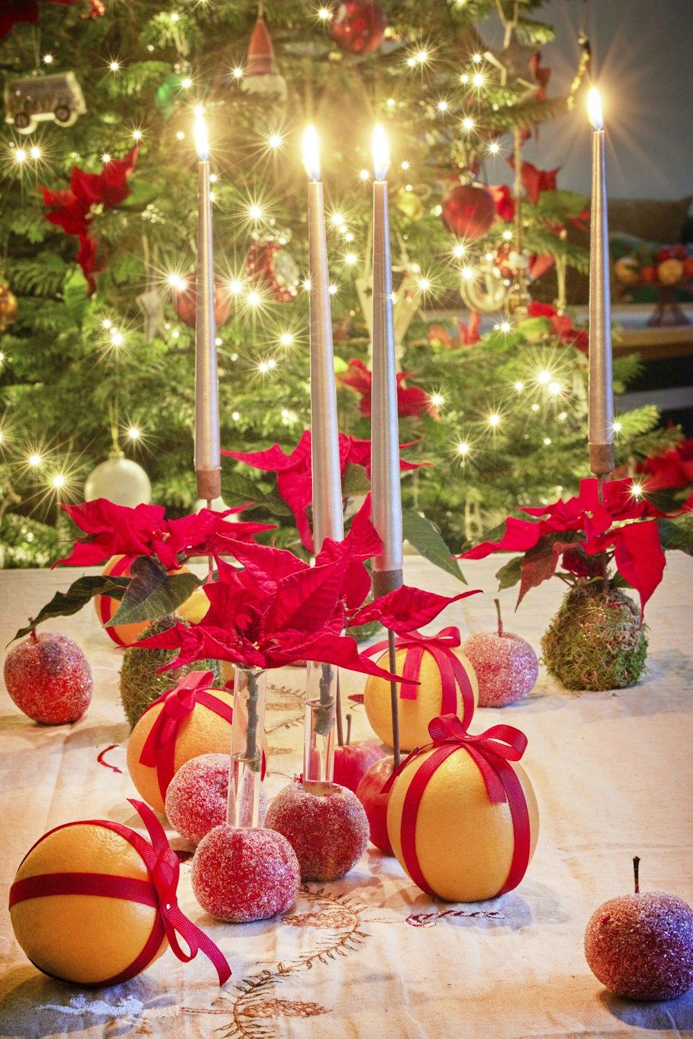 a table topped with apples and candles next to a christmas tree