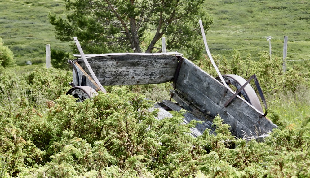 um velho carrinho de madeira sentado no meio de um campo