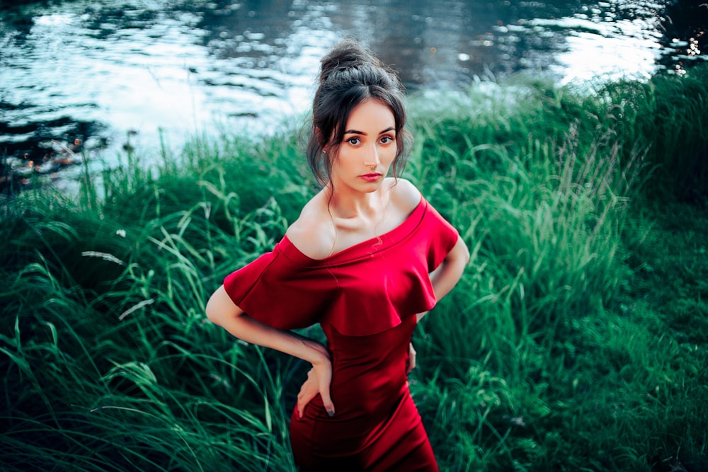 a woman in a red dress standing in front of a body of water