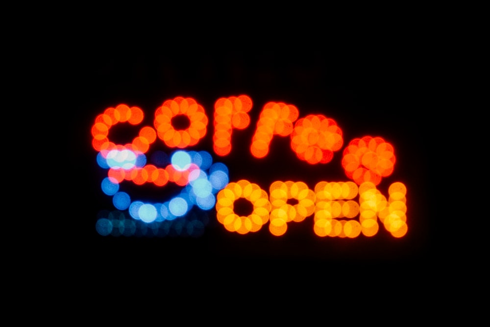 a close up of a neon sign that says coffee and open