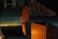 Large industrial structures with dark metallic surfaces and orange lighting. Geometric shapes and angular forms are prominent, set against a dark background. The image conveys a sense of technology or architecture.