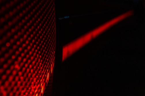 Close-up of sharp-edged legal papers under deep red lighting reflecting on metallic surfaces.