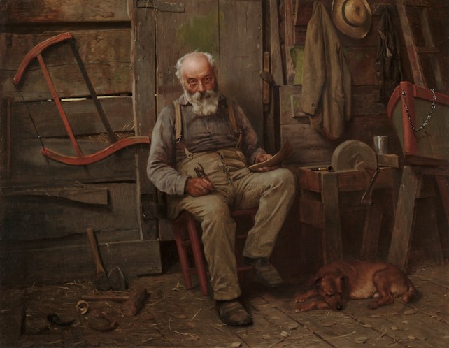An elderly man with a white beard sits in a rustic cabin, holding a small object in his hand. He is dressed in casual work clothes and rests on a wooden chair. Around him are various tools, a hat hanging on the wall, and a sleeping dog lying on the wooden floor. The setting gives a sense of an old workshop or a shed.