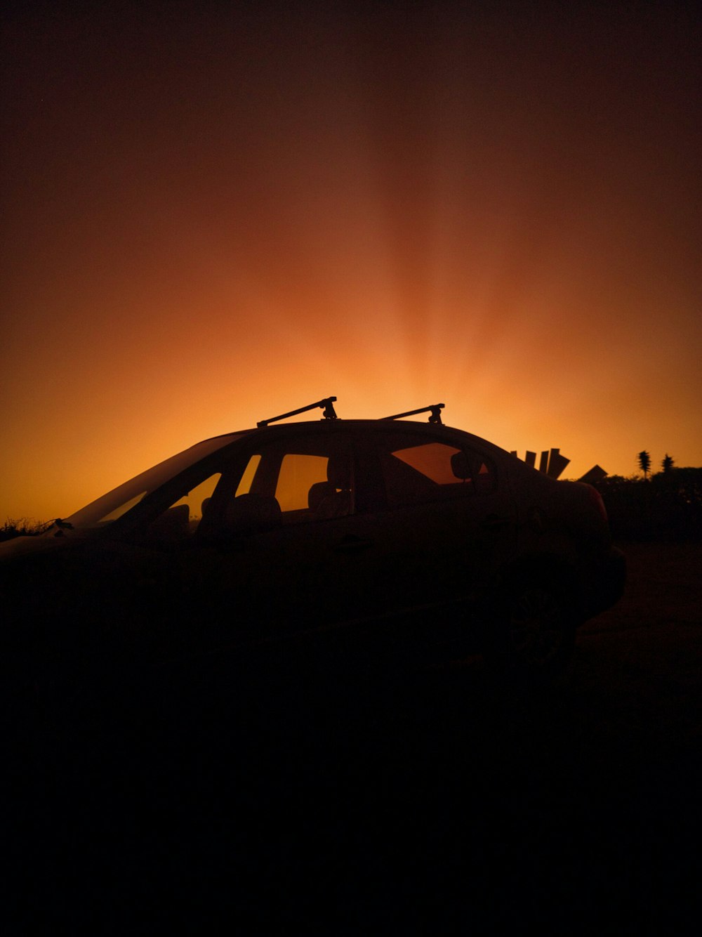 the sun is setting behind a car in the dark