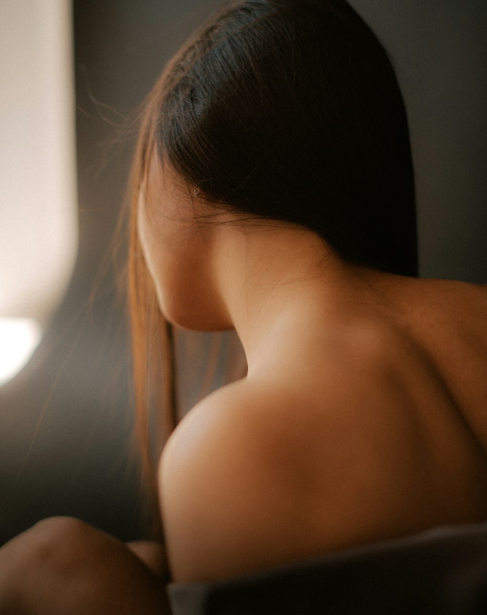 a close up of a woman's back with a window in the background