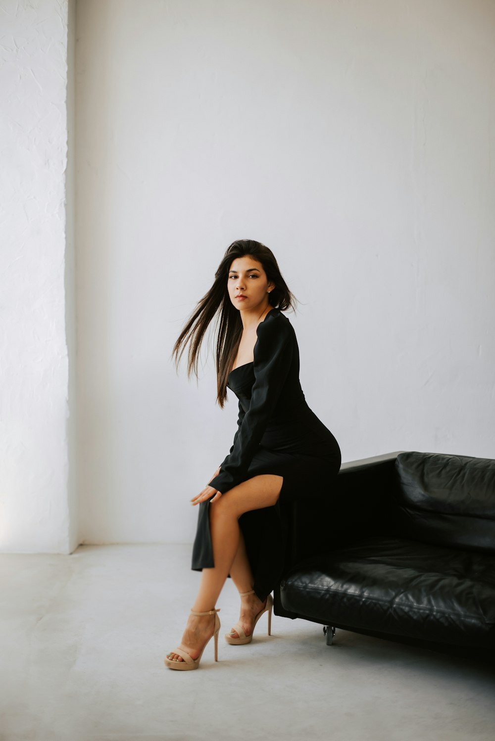 a woman in a black dress sitting on a black couch