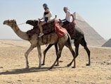 a couple of people riding on the back of a camel
