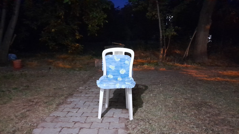 a blue and white chair sitting on top of a brick walkway