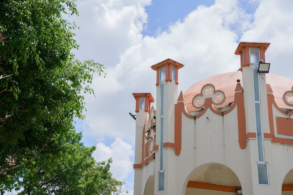 a white and orange building with a tree in front of it