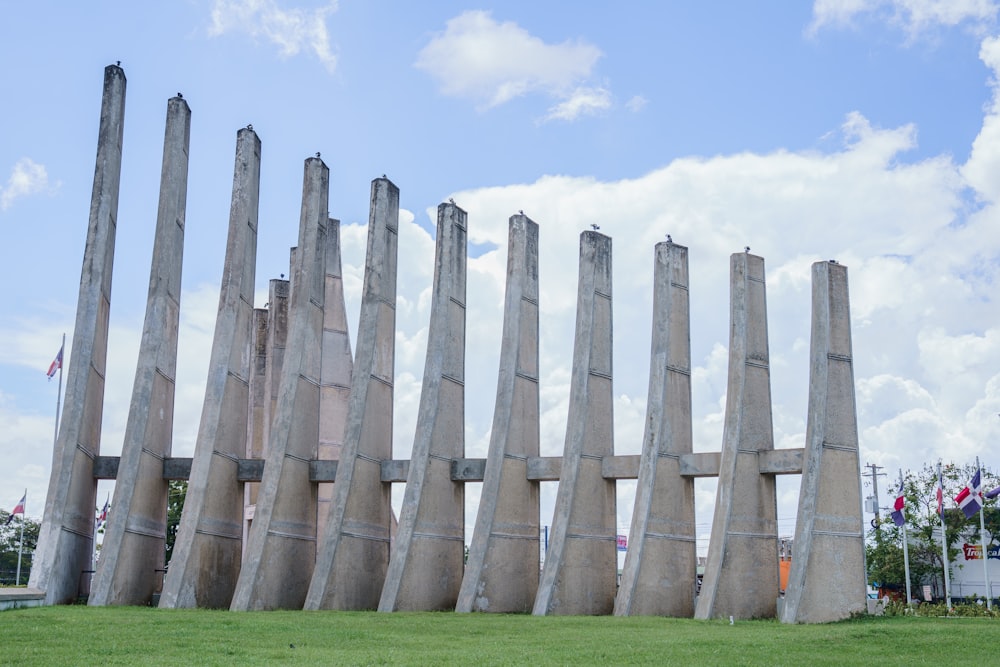 a row of concrete pillars sitting on top of a lush green field