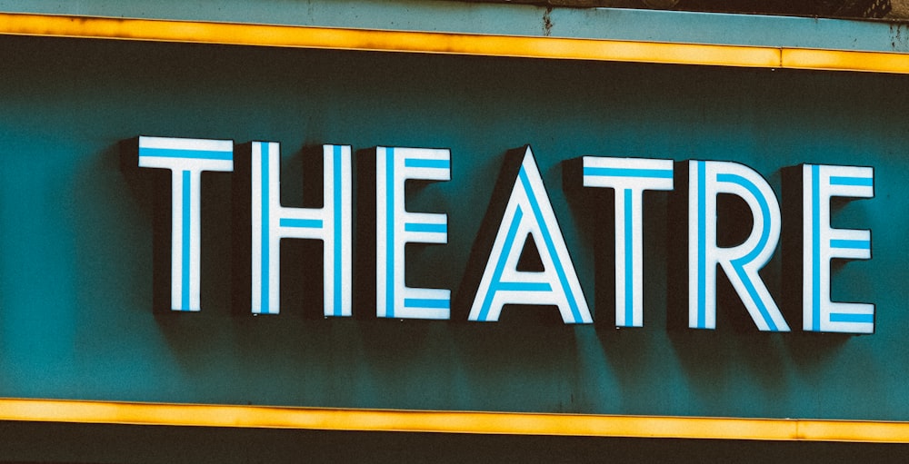 a sign that says the theatre on the side of a building