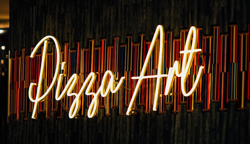 a neon sign on a black wall that says pizza hut