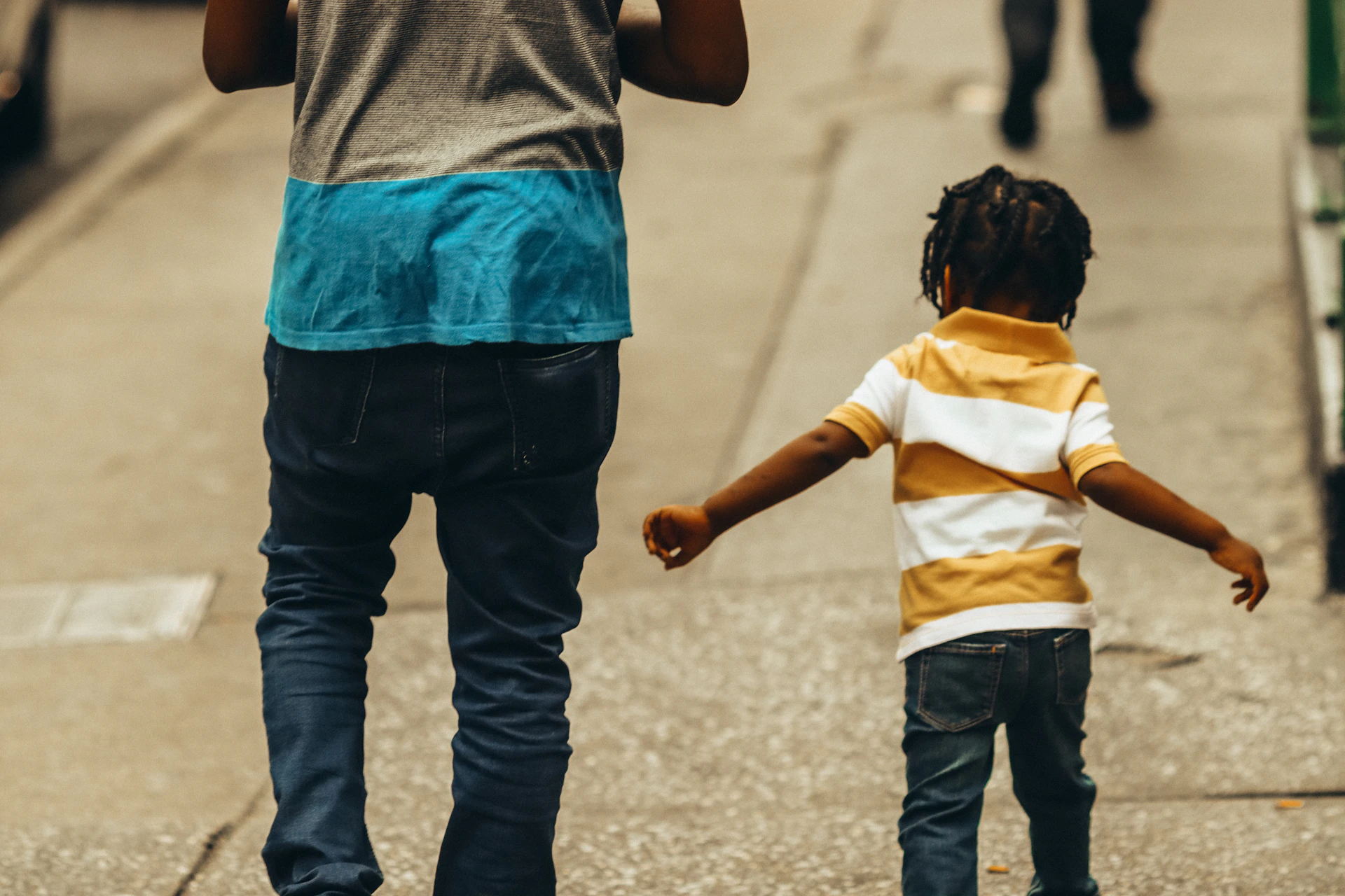 An adolescent walking outdoors with a supportive adult giving advice in a casual, friendly manner.