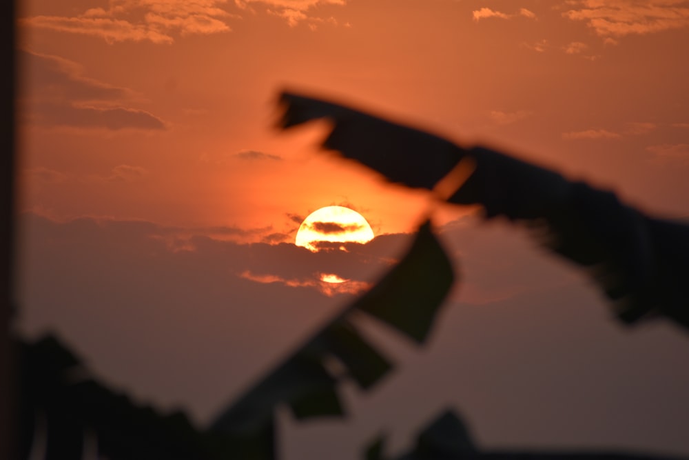 the sun is setting in the sky behind a building