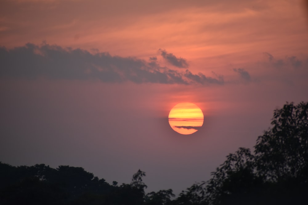 the sun is setting over the trees in the distance